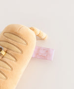 Close-up of the pink cggcw tag on the side of the Pusheen Baguette Reusable Bag Keychain Plush. 