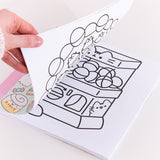 Model holds open the Pusheen activity book showcasing one of the coloring pages. The open page shows a black outline Pusheen as a vending machine with various spheres inside. The vending machine has a turn knob and opening slot for the user to grab the ball. The black outlined graphic is printed in the center of the white page.  