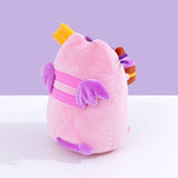 Back quarter view of Pusheen Devil’s Food Cake plush. This view shows Pusheen’s back stripes, plush purple wings, and brown cake peeking out the side.  