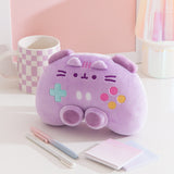 Gaming controller plush sits on a desktop. The purple plush has darker purple trigger buttons on top of the plush and joysticks near the bottom of the plush. 