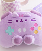 Close-up of the facial embroidery on the front of the purple plush. Pusheen the Cat's eyes, mouth, and whiskers are embroidered in dark purple while her three head stripes between her plush ears are a lighter purple. 