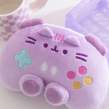 Close-up of the embroidery detail on the gaming controller plush toy. teal, white, pink, and yellow controller buttons are located near the middle bottom of the plush.