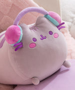 Side quarter view of the gaming squisheen. Pusheen the cat lazes while wearing a pair of multi-colored pastel headphones.