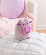 Side quarter view of the Gamer Pusheen Plush. The gray cat has a pink embroidered blush that sits under her purple eyes and mouth.