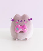 Front view of the Gamer Pusheen Plush toy. The grey cat has a purple hue and sits on her bottom so her four paws can be seen from the front.