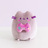 Front view of the Gamer Pusheen Plush toy. The grey cat has a purple hue and sits on her bottom so her four paws can be seen from the front.