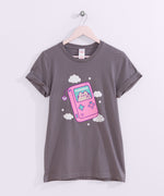 Handheld gaming console printed on a grey tee with the short sleeves rolled up that hangs on a light pink hanger. 