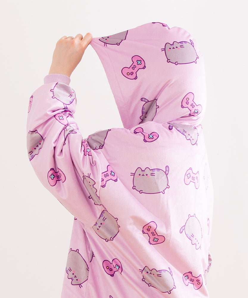 Close-up of the all-over-print on the Gamer Pusheen Wearable Blanket Hoodie. On top of the purple background are pink gaming controllers with multi-colored buttons.
