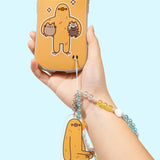 Sloth Phone Charm is attached to a Sloth Phone Case. The beaded string is inserted in the intended slot at the bottom right of the phone case.  
