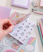 Back cover of the Mini Coloring Cuteness: A Pusheen Coloring & Activity Book. The white-colored background has a pattern of pastel graphics of Pusheen climbing an ice cream cone, Pusheen as a ghost, Pusheen as a strawberry milk carton, a teapot, candy, and more. The book has a light pink spine. Print on the bottom of the cover is the publisher, a UPC code, and pricing information.