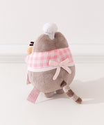 Back quarter view of plush. Pusheen wearing a baking apron stands upright on two pudgy paws. 