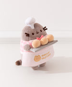 Side quarter side view of Baker Plush. Pusheen the Cat holds three biscuit buns on a light gray platter. 