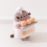 Side quarter side view of Baker Plush. Pusheen the Cat holds three biscuit buns on a light gray platter. 