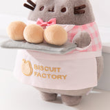 Close-up view of the apron Pusheen wears that says, “Biscuit Factory” accompanied by a cat head outline logo. 