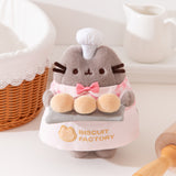 Pusheen the Cat Plush holds a tray of three fluffy golden biscuit on a gray tray.