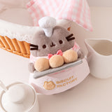 Top aerial view showcasing Pusheen’s face, fuzzy coat texture, and her white patisserie chef hat that sits between her triangular ears. 