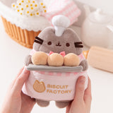 Model holding Biscuit Baker Pusheen Plush to show size scale. The sides of the plush fit in the model’s hands while the head and legs are not encompassed by the hands. 