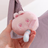 Pink plush keychain with paw prints held in a hand against a light background.