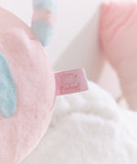 Close-up of the cggcw logo tag that is attached to the back bottom of the plush.