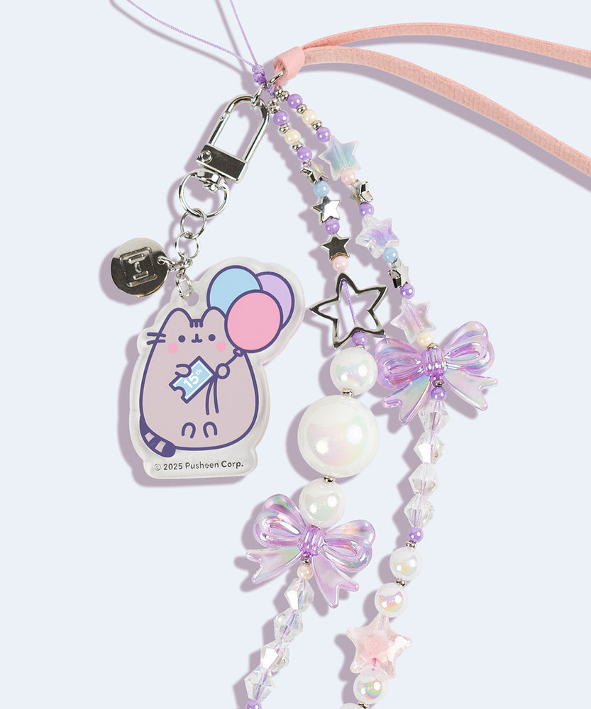 Close-up of the acrylic pastel removable charm on the Pusheen 15th Anniversary Beaded Phone Charm. The charm depicts a pastel-hued Pusheen the Cat holding blue, pink, and purple balloons. 
