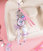 Festival phone charm attached to a white bag. The wristlet has a mix of light purple, light pink, light blue, and white beads alternating on the entire string.