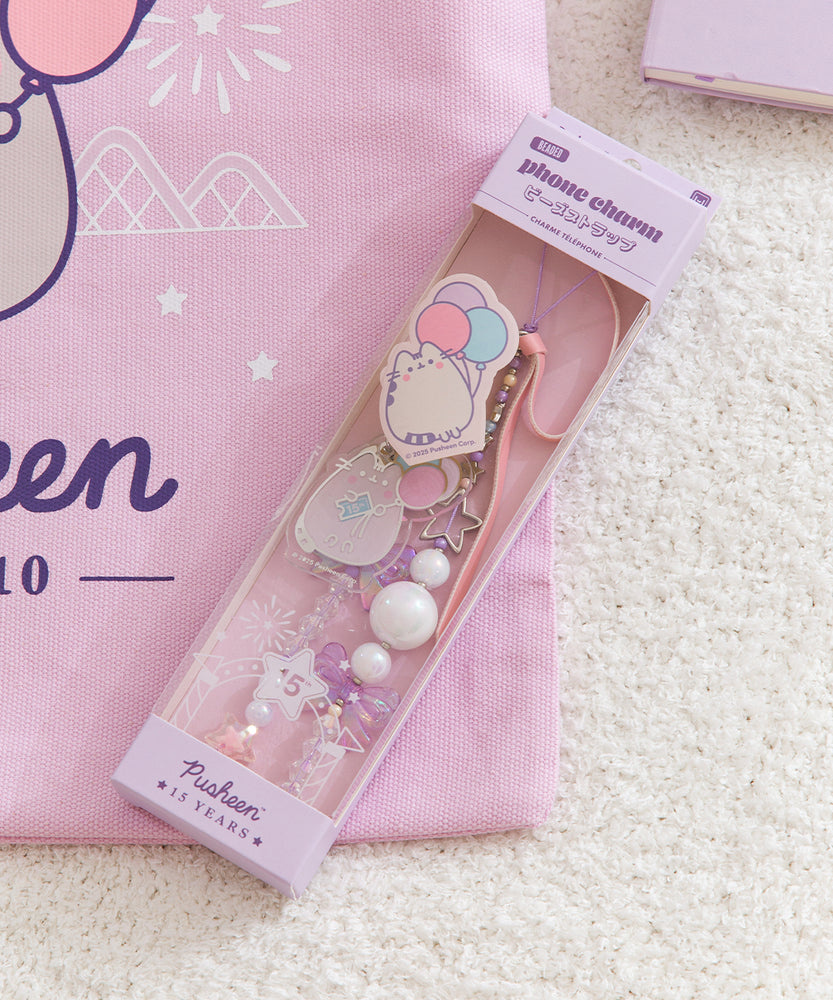 Beaded Phone Charm within purple packaging. The light and dark purple  and white paper has "beaded phone charm" on the topfront and the Pusheen 15 Years logo on the bottom front.