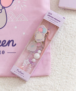 Beaded Phone Charm within purple packaging. The light and dark purple  and white paper has "beaded phone charm" on the topfront and the Pusheen 15 Years logo on the bottom front.