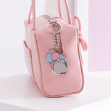 Silver pusheen keychain hangs off a pink zipper purse to show size and scale of the cat keychain. 