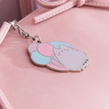 Silver 15th anniversary keychain lies flat on a pink purse to show the reflective finish of the cat.