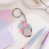 Pusheen keychain charm with flat split ring attached to a chain and decorative Pusheen plate. A blushing grey cat sits in front of pink, purple, and blue balloons. 