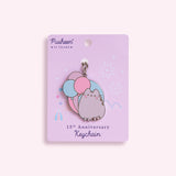 Pusheen 15th Anniversary Keychain on its light purple backer card depicting a pastel fair ground scene. 