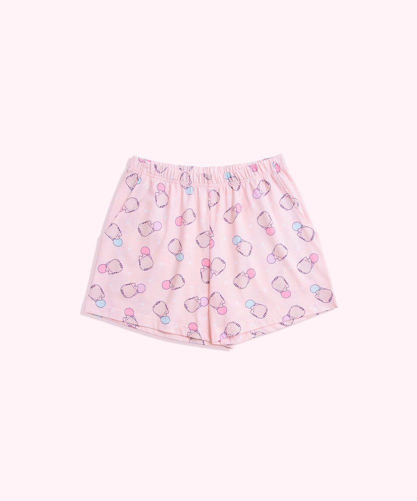 Lying on a background, the Pusheen Pajama Shorts are shown in full. The light pink shorts have an elastic waistband and an all over print of Pusheen the Cat.