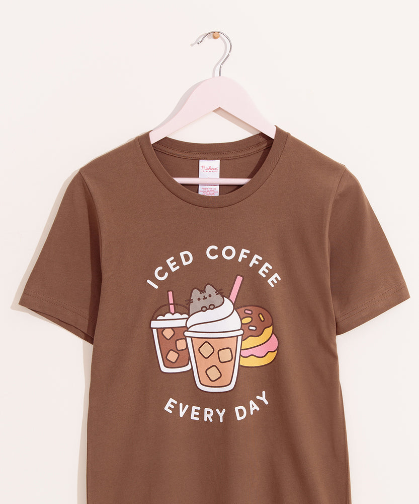 Brown t-shirt with a large graphic on the front center. The graphic shows Pusheen the Cat nestled in the whipped cream of an iced coffee with pink straw.