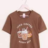 Brown t-shirt with a large graphic on the front center. The graphic shows Pusheen the Cat nestled in the whipped cream of an iced coffee with pink straw.