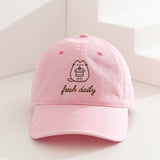 Pusheen Sweets Cap on a white surface. The light pink cap features Pusheen the Cat in a pink hue while outlined by a dark brown color. The phrase "fresh daily" sits below the cat embroidery. 