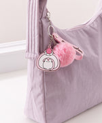 Dessert-themed keychain on a purple purse. The pink and white swiss roll keychain is made out of silicone.