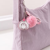 Dessert-themed keychain on a purple purse. The pink and white swiss roll keychain is made out of silicone.