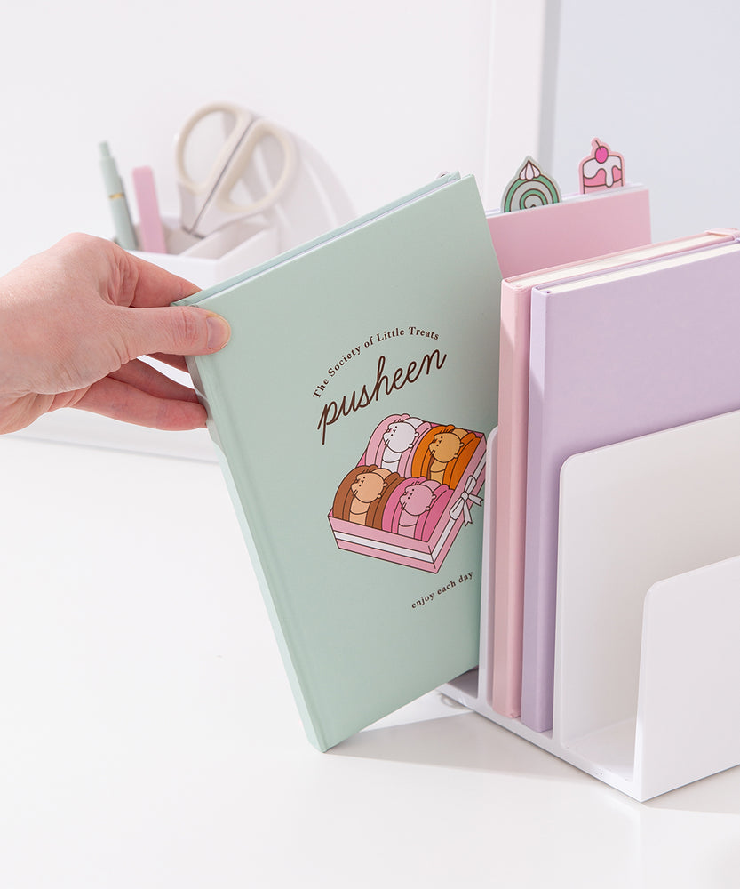 Model places the Pusheen notebook in a file divider to show size of the the mint green sweets-themed notebook.