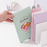 Model places the Pusheen notebook in a file divider to show size of the the mint green sweets-themed notebook.