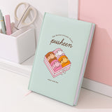 Pusheen Notebook rests on a wall to show the size of the notebook and the amount of lined pages included the luxury notebook.