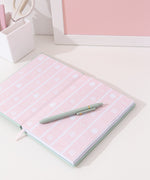 Interior view of the notebook. The inside cover features a pink striped print with macarons, cakes, whipped creams topped with strawberries and two colored Pusheen the Cats in a sitting pose.
