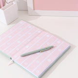 Interior view of the notebook. The inside cover features a pink striped print with macarons, cakes, whipped creams topped with strawberries and two colored Pusheen the Cats in a sitting pose.