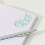 Close-up of the green graphic printed on the top right of each page in the green notebook. The graphic features Pusheen transformed into a swiss roll and a layered parfait. 