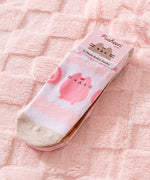 Pusheen Sweets 3-Pack Ankle Socks in their top cardboard packing lying on a pink surface. The strawberry-themed socks are on top of the set of 3.