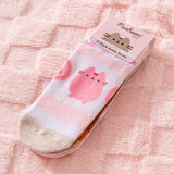 Pusheen Sweets 3-Pack Ankle Socks in their top cardboard packing lying on a pink surface. The strawberry-themed socks are on top of the set of 3.
