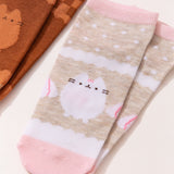 Close-up view of the graphics on the vanilla socks. The white and beige socks have pink accents including Pusheen the Cat in a white color next to some whipped topping piles. 