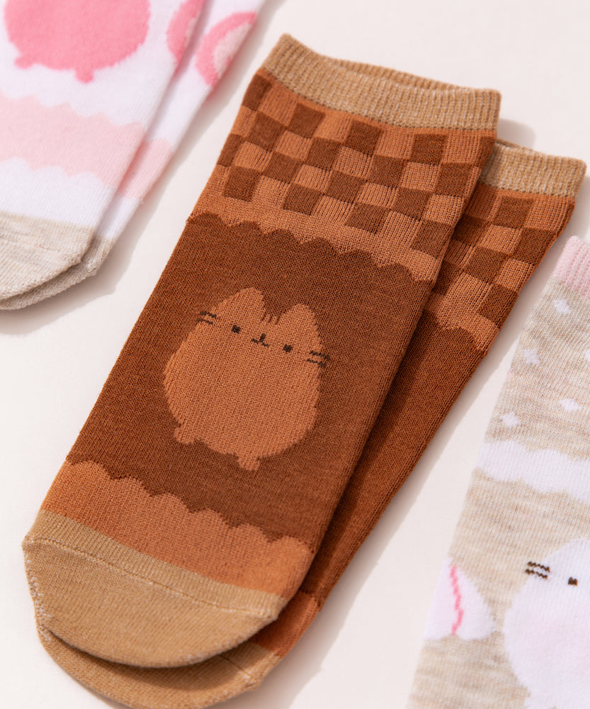 Close-up view of the graphics on the chocolate socks. The two-toned brown socks show Pusheen the Cat in a chocolate color below a brown grid pattern. 