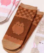Close-up view of the graphics on the chocolate socks. The two-toned brown socks show Pusheen the Cat in a chocolate color below a brown grid pattern. 
