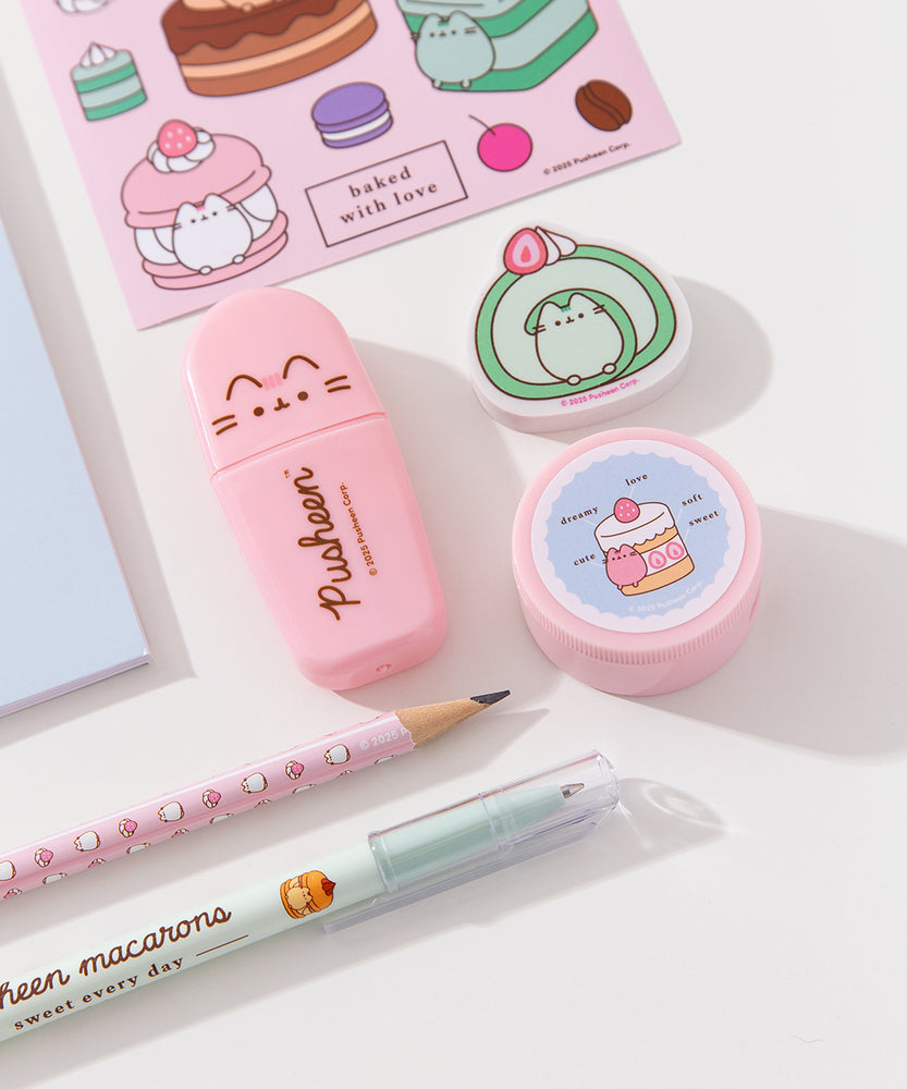 Close-up view of the contents of the Pusheen Sweets Stationery set. The pencil, pen, stickers, eraser, pencil sharpener, and highlighter include graphics and prints of Pusheen the Cat as various sweet dessert characters and flavors including a strawberry, lavender, chocolate, matcha, vanilla, and cherry.