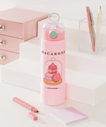 Front view of Pusheen Water Bottle. On the front of the bottle is a graphic of three macarons in a pastry case. Above the graphic is the phrase "macarons" while below the graphic is the phrase "sweet moments."